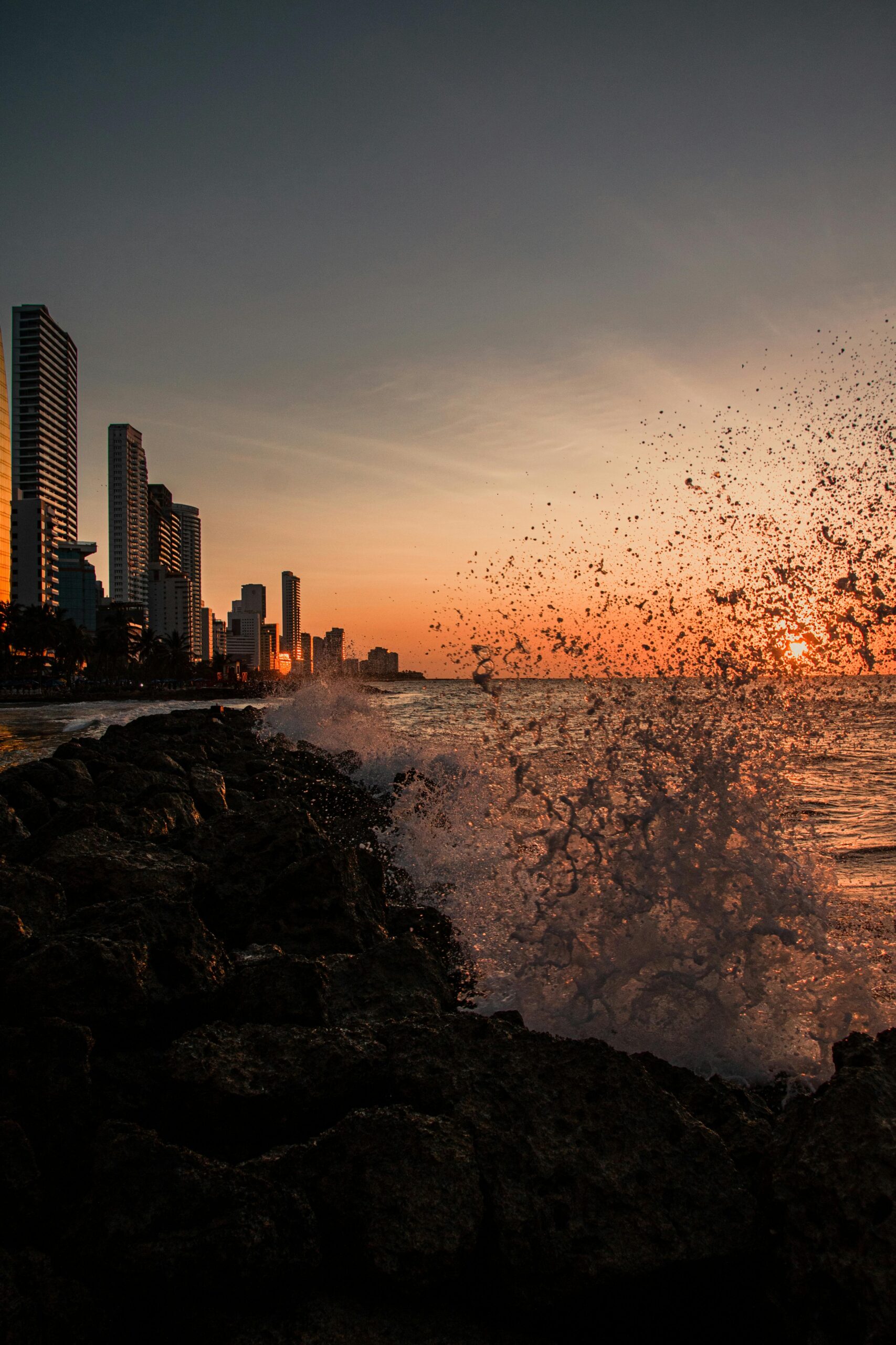 Breathtaking sunset view of Cartagena, Colombia skyline with crashing ocean waves.